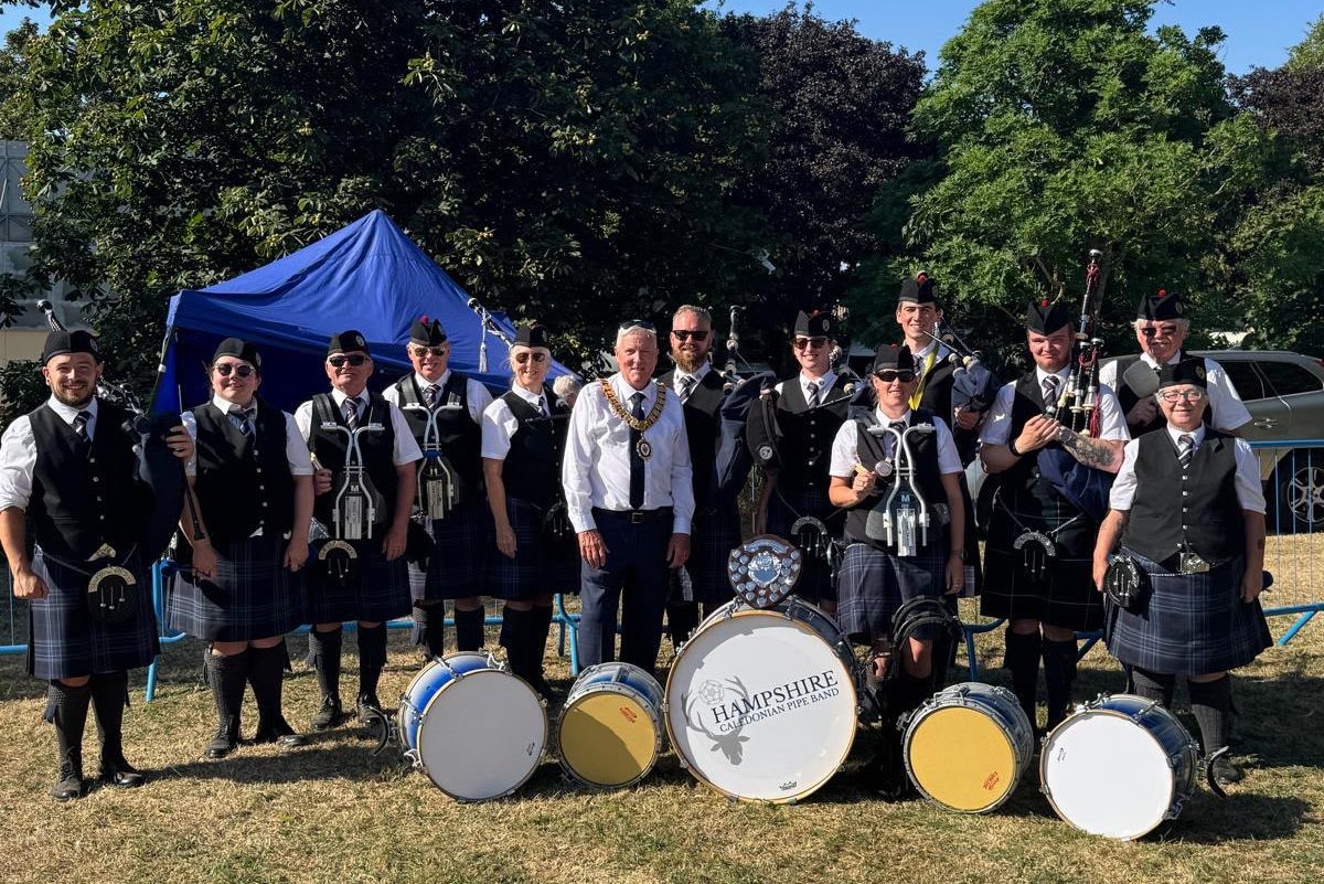 Hampshire Caledonian Pipe Band having a picture taken following a successful competition at Corby Highland Gathering, with their trophy.